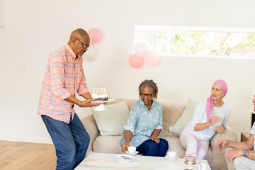 Senior friends celebrating birthday at home with cake and joyful smiles