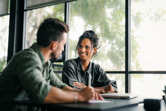 Two happy diverse multiethnic business team people working, talking in corporate office