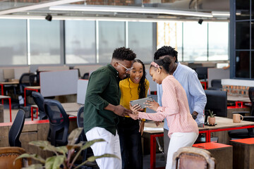 Team collaborating in modern office, excitedly discussing project on digital tablet