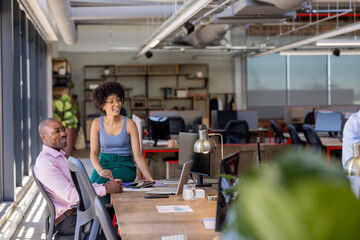 Colleagues collaborating at modern office desk, discussing project with enthusiasm