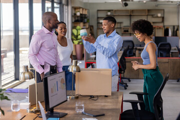 Obraz premium Celebrating teamwork with gift, African American colleagues smiling in office