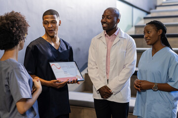 Discussing award certificate, medical professionals smiling and engaged in hospital hallway