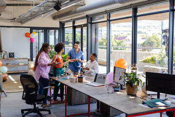 Celebrating teamwork success, African American colleagues with cake in modern office