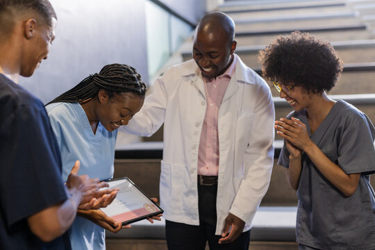 Celebrating colleague's award, medical team showing appreciation in hospital hallway