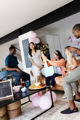 Friends celebrating at home, exchanging gifts and enjoying drinks with laughter