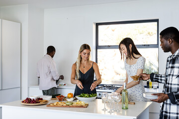 Friends preparing food and setting table for celebration in modern kitchen
