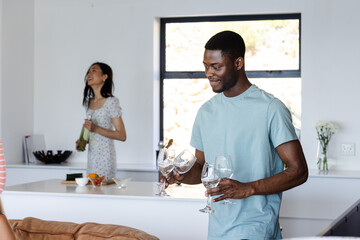 Friends preparing drinks and laughing together in modern kitchen during celebration