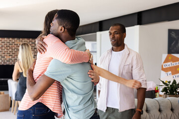 Hugging friend during celebration, African American man with others smiling nearby