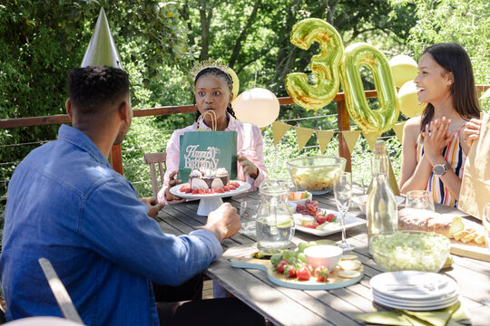 Celebrating birthday outdoors, friends enjoying cake and decorations with joy
