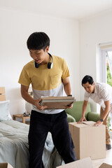 Father and son unpacking boxes in bedroom, enjoying new home together