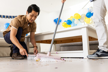 Father and son cleaning living room floor after birthday party celebration