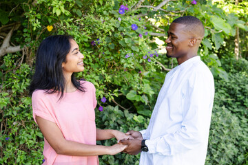 Couple holding hands and smiling at each other in lush garden setting
