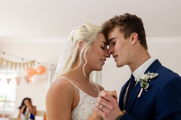 Bride and groom sharing intimate dance, smiling and holding hands at reception
