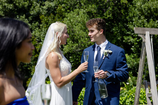 Bride and groom toasting with champagne outdoors, smiling and celebrating together