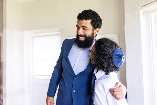 Father and son embracing joyfully during bar mitzvah at home