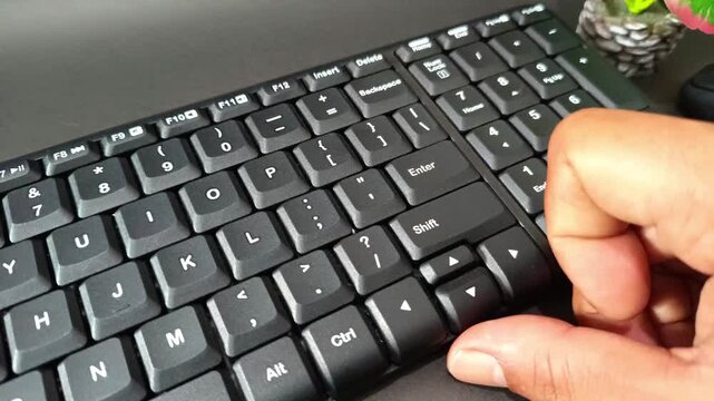 Footage of a finger pressing the Enter key on a modern black mechanical keyboard with a unique key design.