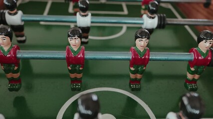 detailed close up of foosball table figurines in red jerseys facing opponents in white