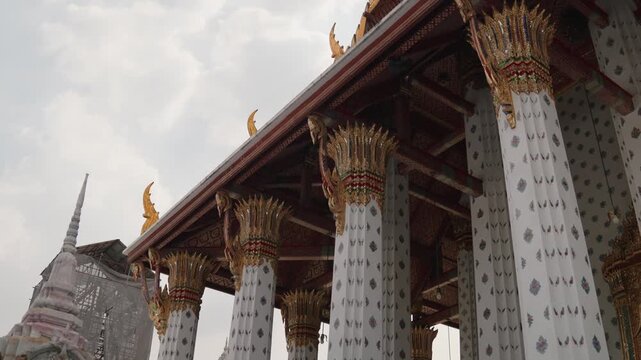 Intricately designed Thai temple architecture featuring lavishly adorned columns and graceful, elegant rooflines