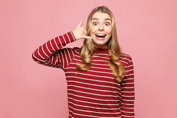 Young shocked surprised fun happy woman she wearing red striped sweatshirt casual clothes doing phone gesture like says call me back isolated on plain pastel light pink background. Lifestyle concept.