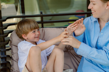 A joyful child interacts with an adult in a relaxed outdoor setting. They are both engaged in a playful activity on a comfortable swing, sharing smiles and laughter.