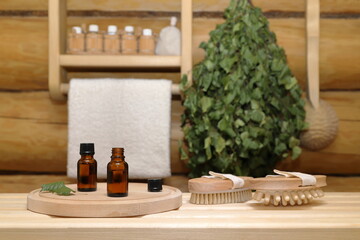 On a plank bench there are two bottles of healing essential oil on a wooden round tray next to a...