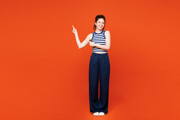 Full body young smiling woman she wears blue striped tank top casual clothes point index finger...