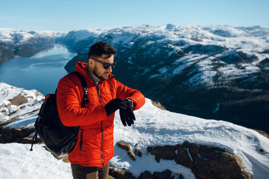 Traveling man backpacker checking time looking smartwatch in mountains