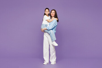 Full body young smiling woman wear blue casual clothes have fun with child baby girl 8-9 years old. Mommy hold little kid daughter in hands isolated on plain purple background. Mother's Day concept.