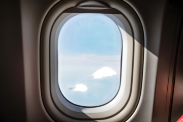 Looking out the window of an airplane at the blue sky and white clouds during flight isolated on transparent background