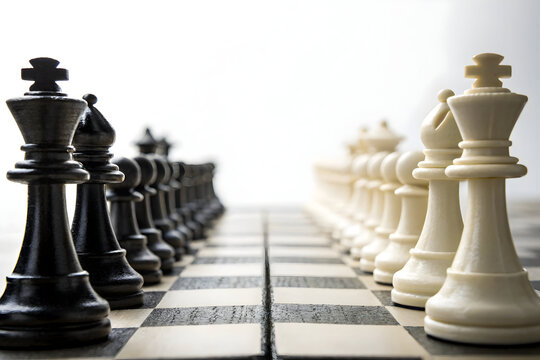 Black and white chess pieces lined up on a chessboard ready for a game