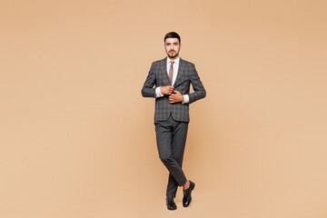 Full body young Caucasian confident successful employee business man corporate lawyer he wear classic formal grey suit shirt tie work in office look camera posing isolated on plain beige background.