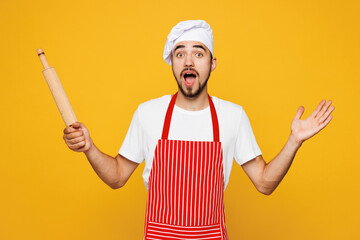 Young shocked surprised housewife housekeeper chef cook baker man he wear red apron toque hat hold...