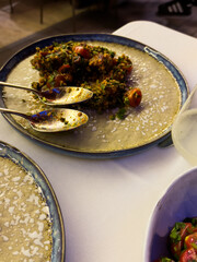 Tabbouleh salad on a plate in a restaurant, food from a restaurant. The blue plate has a salad with tomatoes and a spoon