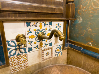 A bathroom sink with a gold faucet and a blue and white tile wall. copper or bronze faucet with...