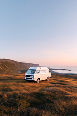 Vintage camper van road trip adventure on scenic coastal highway at sunset