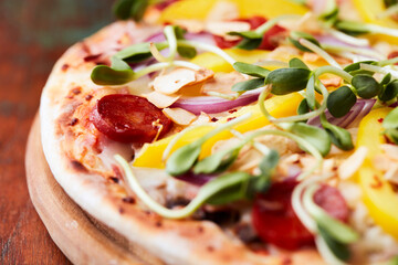 Pizza with chorizo ​​sausage, mozzarella cheese and yellow pepper. Rustic wooden background. Soft focus.	