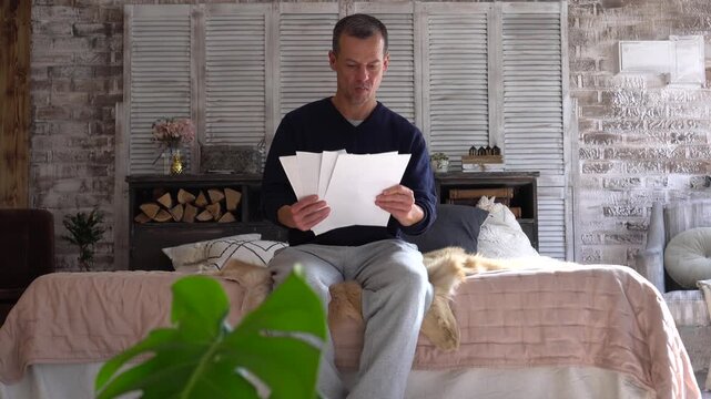 A sad man with papers. Financial crisis, debts, bills, bank statement paper or tax documents