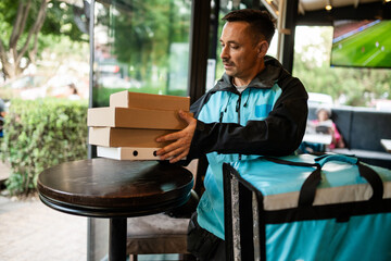 Delivery man placing pizza boxes on table in restaurant