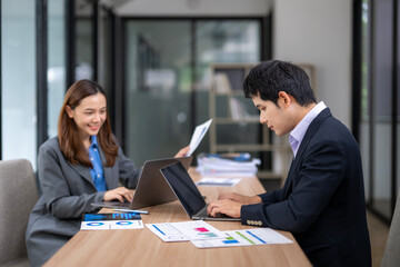 Business people working and typing on laptop in modern office, analyzing charts and reports