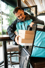 Delivery man taking food boxes from thermal bag in a restaurant