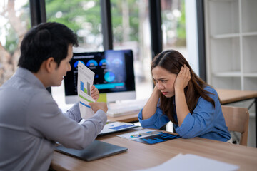Businesswoman covering ears while businessman showing bad financial report in office meeting