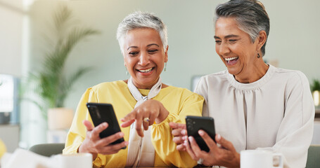 Coffee, laughing and phone with senior friends in living room of home for humor, comedy or visit. App, funny and meme with old women at table together for bonding, joke or reaction to social media