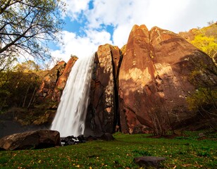 Waterfall cascading down red rock cliffs in autumn foliage