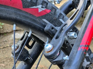 Close up of bicycle wheel with black tire, red frame, and mechanical brake system details