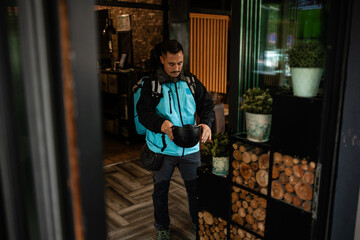 Deliveryman removing helmet entering restaurant after delivery work