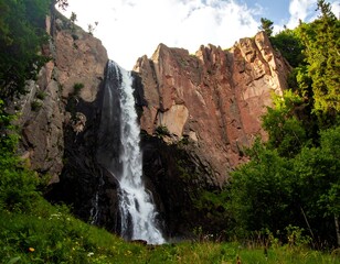 Waterfall cascading down rocky cliff face, lush forest backdrop