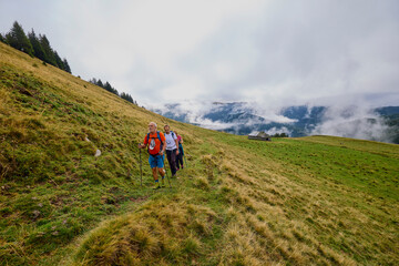 Fototapeta premium a couple with their grandfather walking in the mountains on a cloudy and foggy day.