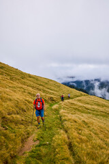 Obraz premium a couple with their grandfather walking in the mountains on a cloudy and foggy day.