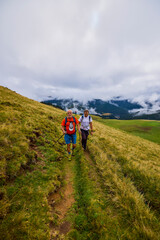 Fototapeta premium a couple with their grandfather walking in the mountains on a cloudy and foggy day.