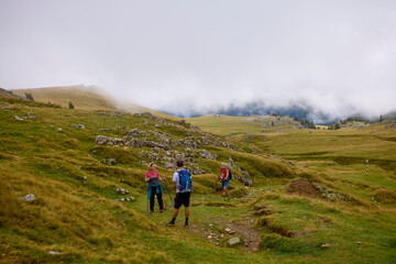 a couple with their grandfather walking in the mountains on a cloudy and foggy day.